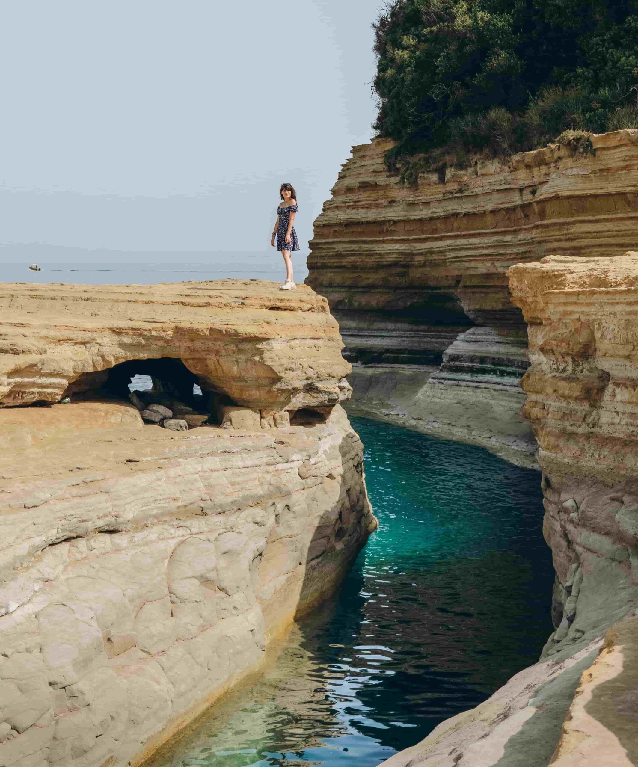 A girl standing on the cliff overlooking the beautiful Canal d'Amour in Corfu, Greece