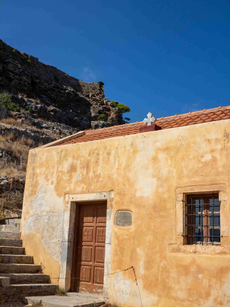 A tranquil countryside scene in Crete, featuring a quaint chapel amidst lush green fields