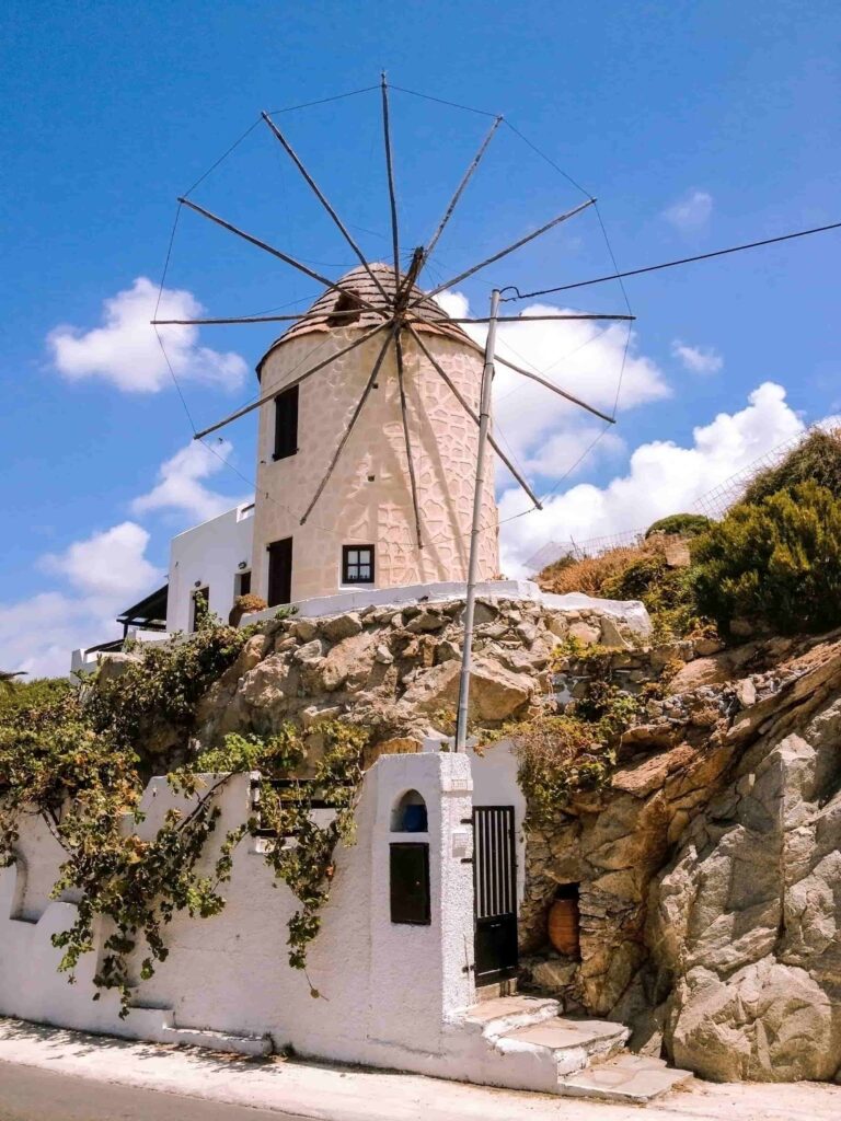A traditional whitewashed windmill in Naxos, Greece, set against a clear blue sky.